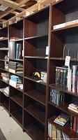 Photo showing three tall dark brown Billy bookcases with multiple shelves. The middle one is empty, others have books and items but are not included in sale.