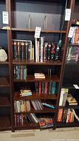 Full bookshelf with various books and some other small items, showing the assortment of book titles and series.