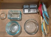 Overview of the lot showing Pyrex glass bowls and Snapware plastic containers with lids, plus metal divided tray.
