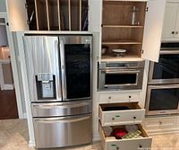 Wide shot of kitchen area with stainless steel refrigerator, open shelving showing glassware and bowls, including Pyrex Vintage Charm bowl and other kitchenware.