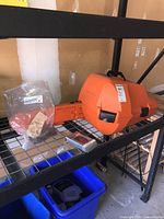 Closed orange hard plastic case on metal shelf with plastic bag containing chain