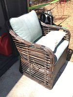 Side angle showing wicker frame and blue-green cushions with decorative pillow on seat.