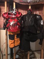 Photo showing hanging adult motocross protective gear and child motocross suit including chest/shoulder protectors and pants