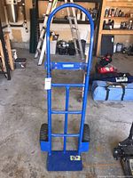 Full front view of blue Mastercraft hand dolly with air tires, showing rounded handle and toe plate.