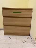 Front view showing three drawers and wood grain finish.