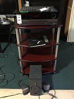 Harman Kardon AVR 254 receiver and speakers on shelving unit with remote control and manual.