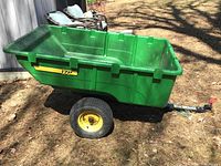 Full side view of green polyethylene tub mounted on black frame with two wheels and tow bar