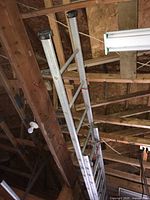 Full length aluminum ladder hanging from ceiling beams in garage