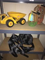 Photo showing yellow Little Tikes dump truck and two bamboo/rattan decorative lanterns on shelf