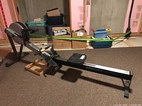 Full side view of gray and black Concept2 indoor rower on aluminum rail in basement setting