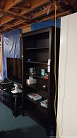 Photo of the shelving unit in a basement setting, showing the front view with some items on shelves.