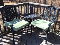 Front view of two chairs flanking a small round table on a wood deck outdoors