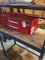 Side view of red metal toolbox with handle on drawer and side handles, showing condition and size.