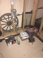 Photo showing tools placed on basement floor near unfinished wall including boxed toe kick saw, drill mixer, and charger stations.