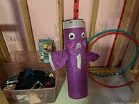 Overview showing the purple punching bag toy, sterilite clothing bin, and hula hoops leaning against wall