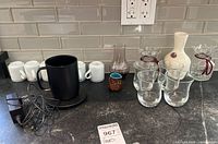 Photo of entire lot with Ember heated mug, Schmidt cups, vases, and clear drinking glasses on countertop.