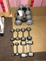Overall view of 4 pairs metal hex dumbbells and 3 pairs plastic dumbbells on stand