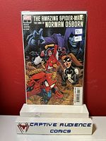 Front cover view of The Amazing Spider-Man: The Sins of Norman Osborn #1 comic book in protective sleeve against red background