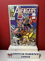 Front cover photo of Avengers #349 comic book in protective sleeve, placed on Captive Audience Comics stand against red background.