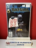 Front cover of Batgirl #2 comic book in protective sleeve against a red background with a white stand labeled 'Captive Audience Comics'.