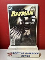 Photo of Batman #634 comic book cover showing Batman artwork with 'Outlaw!' text and condition stickers, sealed in protective sleeve.