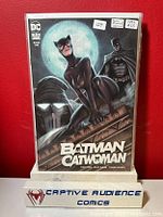 Comic book Batman/Catwoman #1 Ryan Kincmid variant in a protective sleeve, showing front cover featuring Catwoman, Batman, and a full moon, against a red background with Captive Audience Comics stand in front.