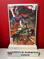 Photo of Batman / Superman #3 Deceased variant comic book in protective casing against a red background with Captive Audience Comics stand.