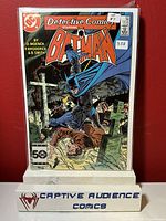Photo of Detective Comics #552 comic book with Batman on cover placed against a red background, displayed with Captive Audience Comics stand.