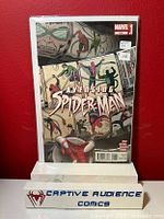 Photo showing Spider-Man comic book issue 15.1 by Marvel in a protective sleeve against a red background with a Captive Audience Comics stand.
