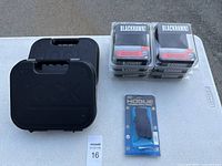 Two black Glock hard plastic cases, six Blackhawk holsters in packaging, one Hogue grip in packaging shown from above on a white table.