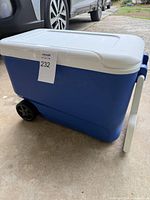Side view of blue Igloo wheeled cooler with white lid and one visible wheel, handle extended.