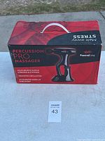 Box of Percussion Pro Massager showing device image, branding, and key benefits including muscle soreness relief and circulation promotion.