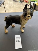 Side front angle of black and white Boston Terrier with red collar cast iron door stopper figurine on black table.