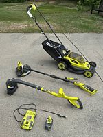All three power tools, battery and charger arranged outdoors on concrete