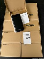 Set of ten cardboard boxed power banks with one power bank and instruction booklet on top shown in detail.