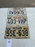 Photo showing three Texas license plates: one Farm Trailer plate and two standard plates with various expiration years and condition mostly used with rust on one plate.
