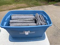Blue plastic tub filled with 10 gray moving blankets, showing some wear and creases on the blankets.