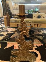 Front view of large antique stylized brass candle holder showing detailed ornate patterns and patina.