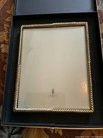 Large silver-toned picture frame with twisted rope design edge inside original black presentation box showing L'OBJET logo.