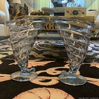 Front view of the pair of shell-shaped glass vases showing their spiral design and pedestal bases.