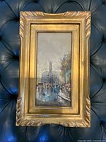 Full view of framed Paris cityscape oil painting showing gold carved frame and vertically oriented image.
