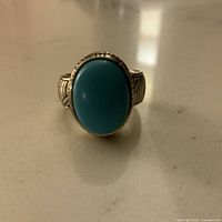 Front view of ring showing large oval turquoise stone and detailed etched silver band.