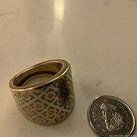 Angle showing wide enamel geometric pattern and size comparison with coin.