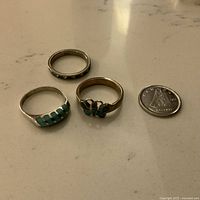 Three vintage sterling silver 925 rings laid on marble surface next to Canadian 10 cent coin for size reference. Includes two turquoise inlaid rings and one eternity band with crystals.
