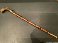 Full length view of the vintage crop or umbrella showing the bamboo shaft with carved segments and the handle end with brass collar and leather strap.