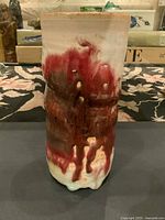 Front view showing the red and brown dripping glaze over white ceramic base of the vase.