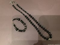 Full view of the vintage black faceted glass bead necklace and bracelet set with sterling silver 925 details, laid out on a flat surface