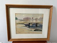 Front view of framed watercolor painting showing a bridge over water with trees in the background, signed by S Honkanan in lower left.