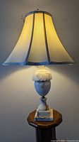 Side view of the illuminated lamp showing the fabric shade and alabaster base on a small stand.