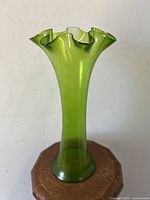 Side profile of green ruffled top vase showing flared neck and smooth glass body.